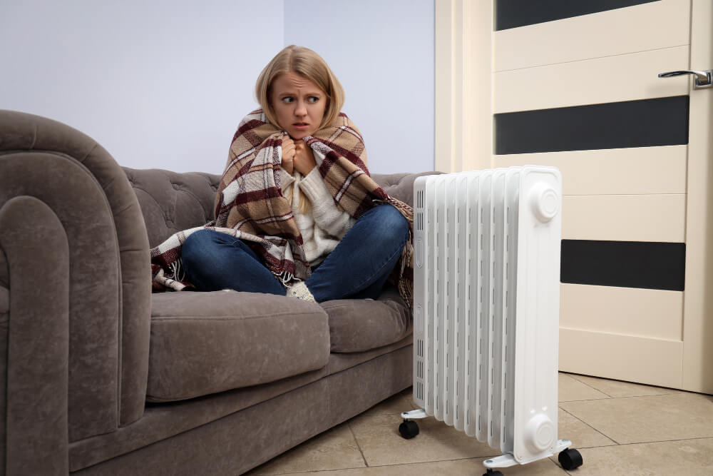 woman sitting on sofa with heater on